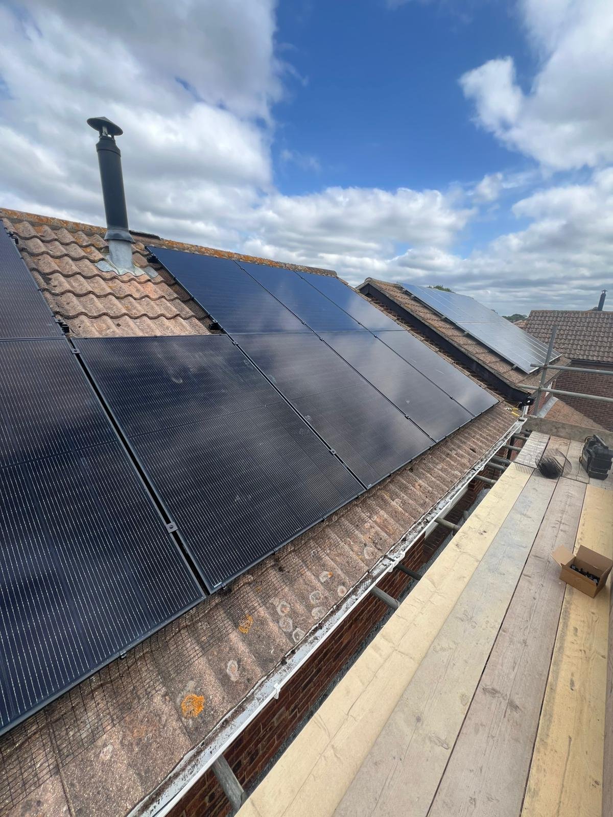 Solar panels with bird mesh and scaffolding on a tiled Hampshire roof