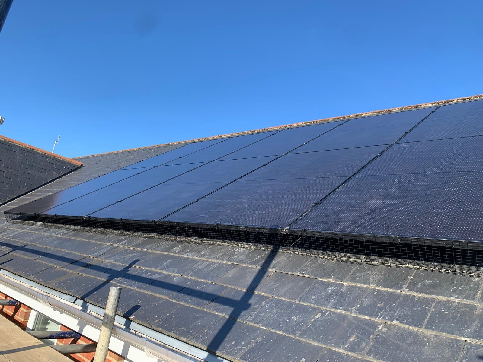 Black solar panels glinting in sunlight on a slate roof in Winchester