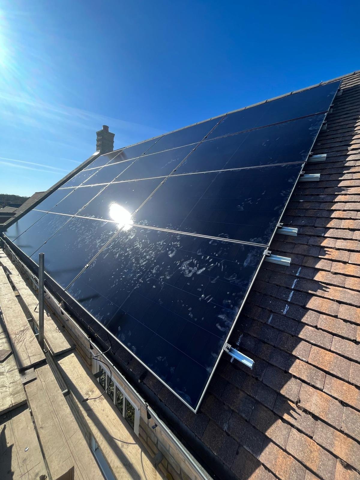 Black solar panels in direct sunlight on a tiled roof in Winchester