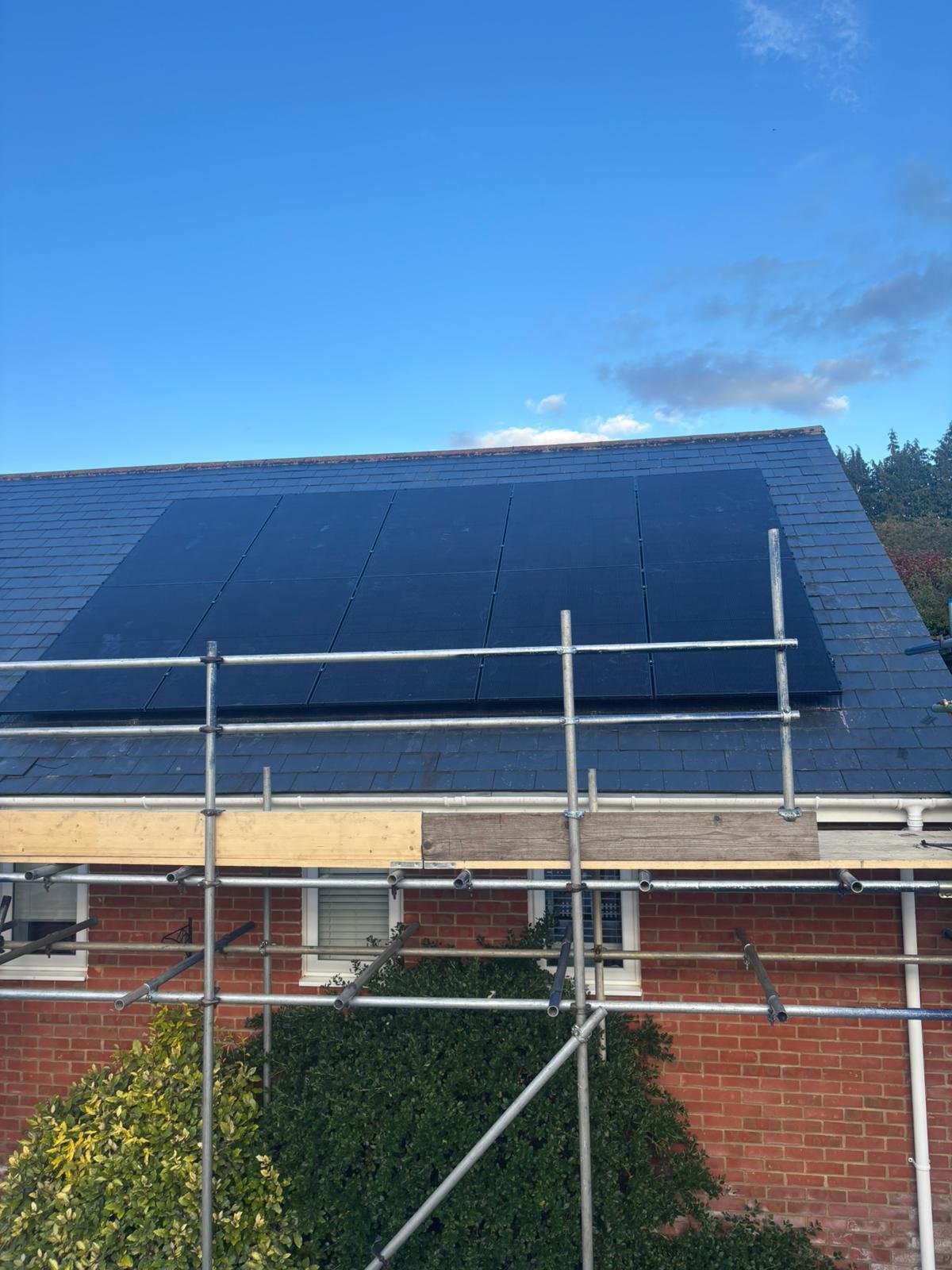 Solar array on a slate roof with scaffolding and safety netting