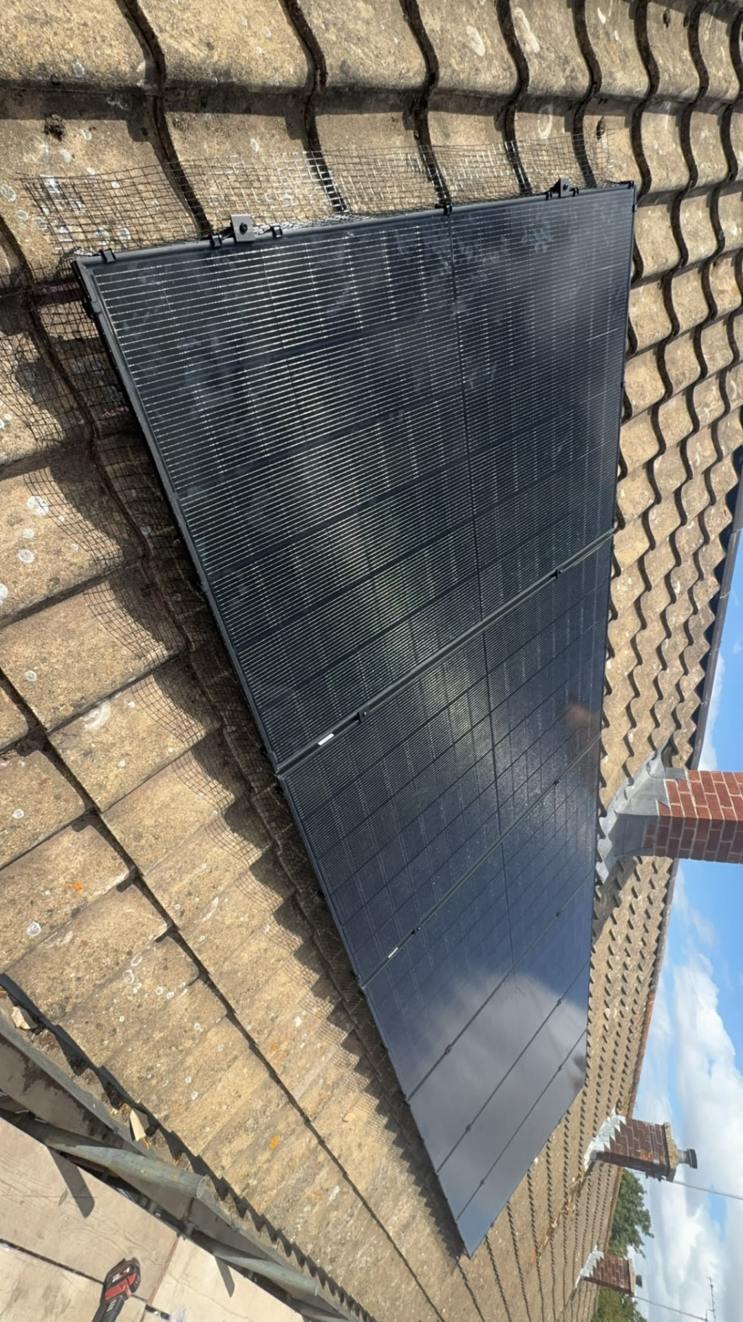 All-black solar panel array fitted to a pantile roof with bird mesh