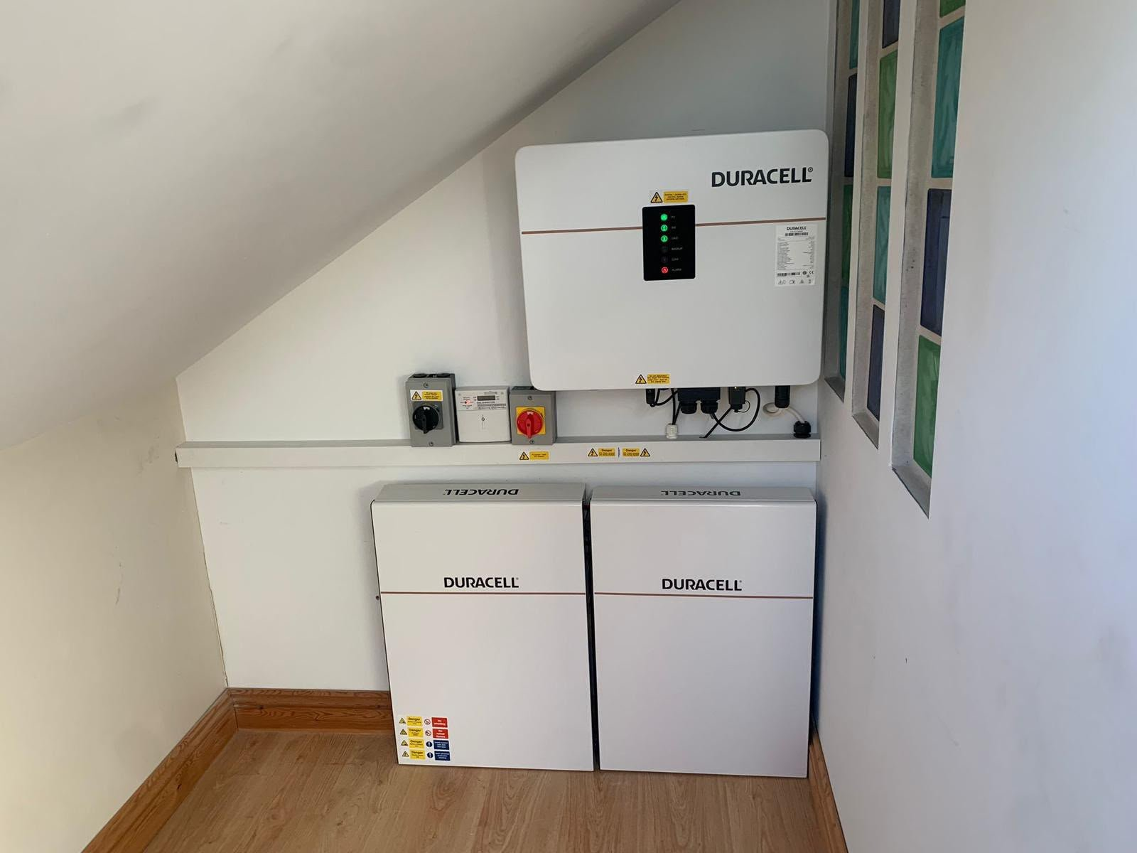Duracell inverter, generation meter and isolators neatly installed above two Duracell home battery units