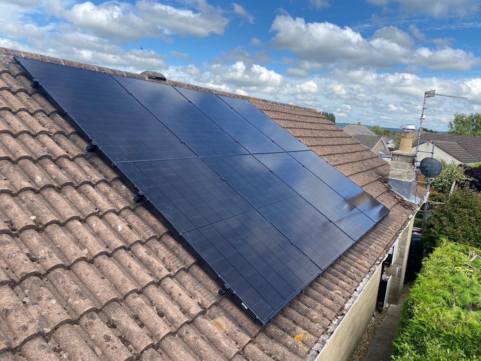 Solar panel array on a light brown tiled roof under blue sky