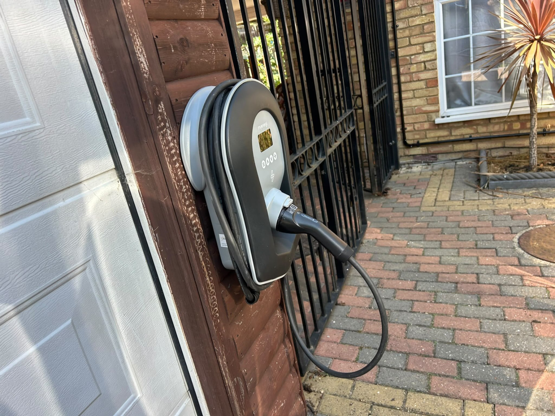 Side view of a Zappi EV charger installed on a timber garage post