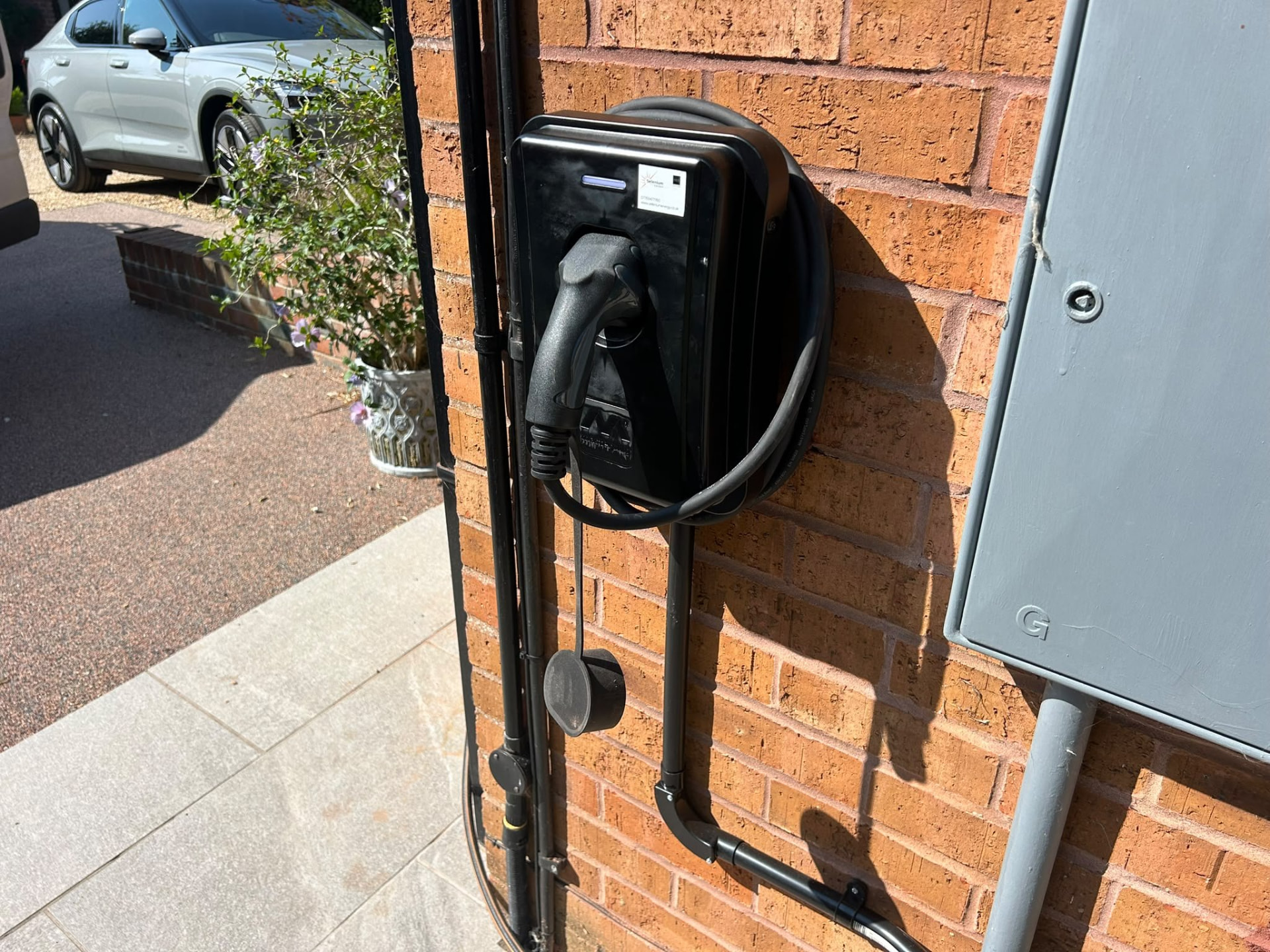 Black EV charge point installed on a red brick wall in Hampshire