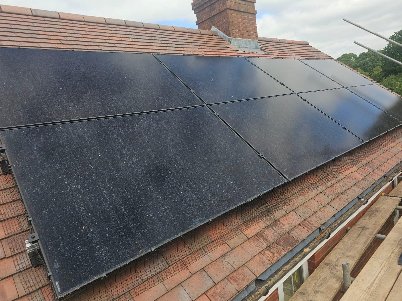 Close-up of solar panels with bird protection mesh on red roof tiles