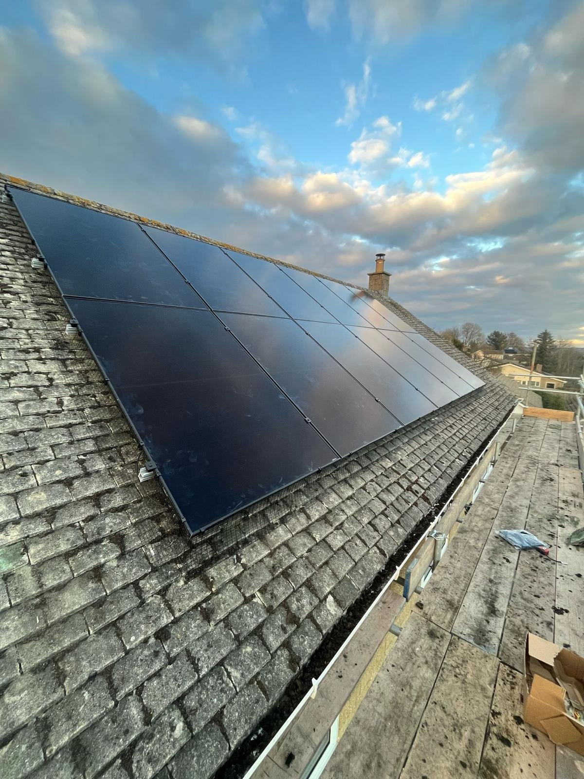 All-black solar PV array installed along a tiled roof slope at sunset in Hampshire